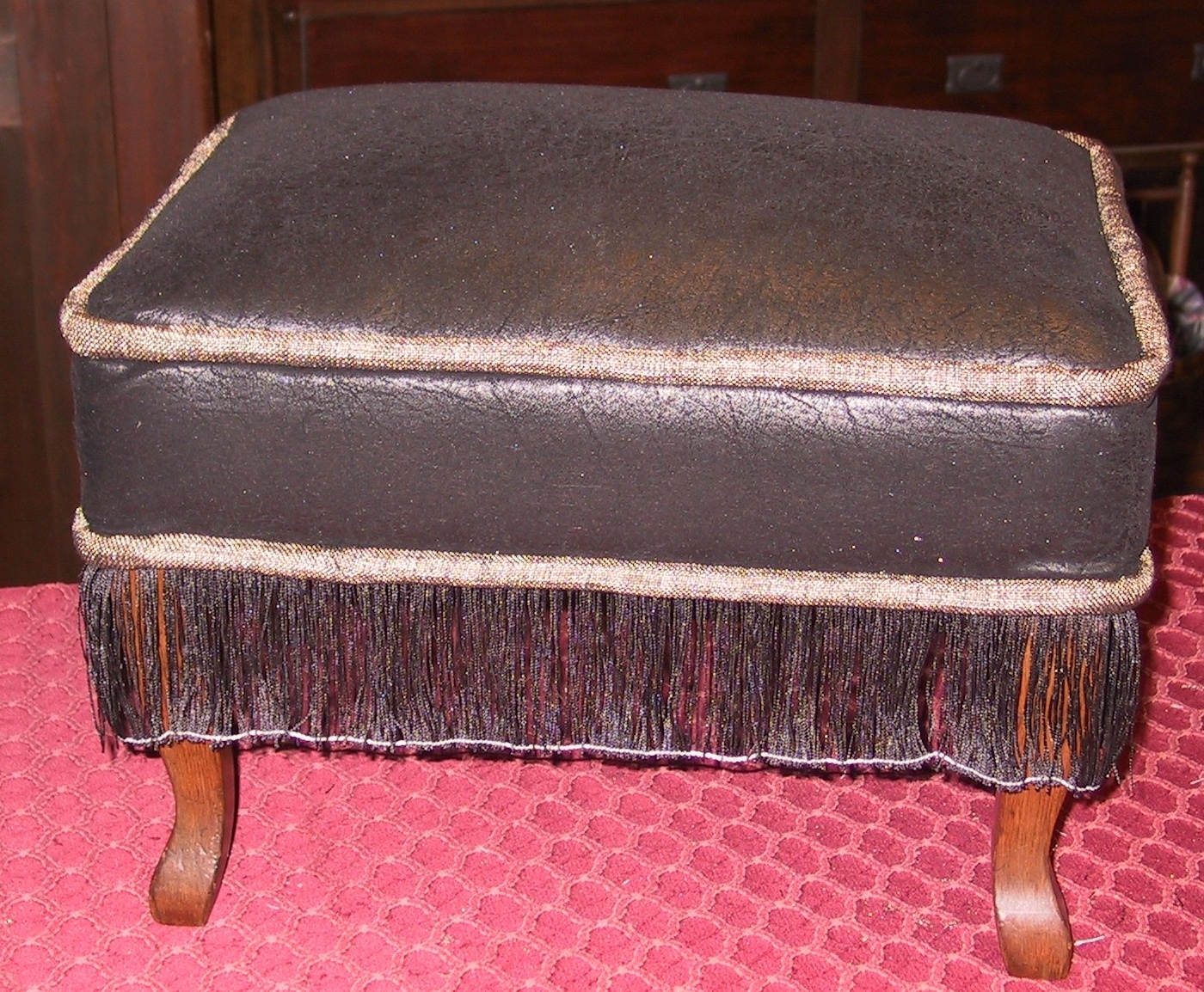 Faux-suede, chenille welt and a fine slurry transform this ottoman. Note That the string had not been removed to free the fringe yet