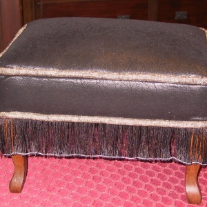 Faux-suede, chenille welt and a fine slurry transform this ottoman. Note That the string had not been removed to free the fringe yet